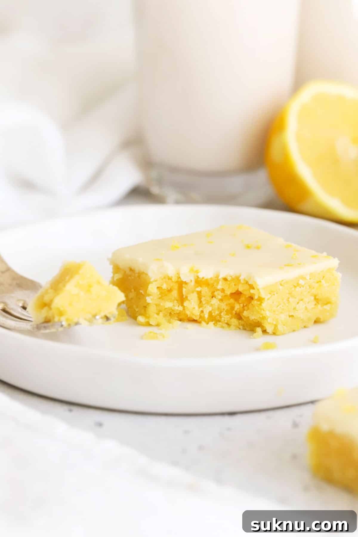 A fork piercing a gluten-free lemon brownie, highlighting its moist, fudgy interior and glossy lemon glaze