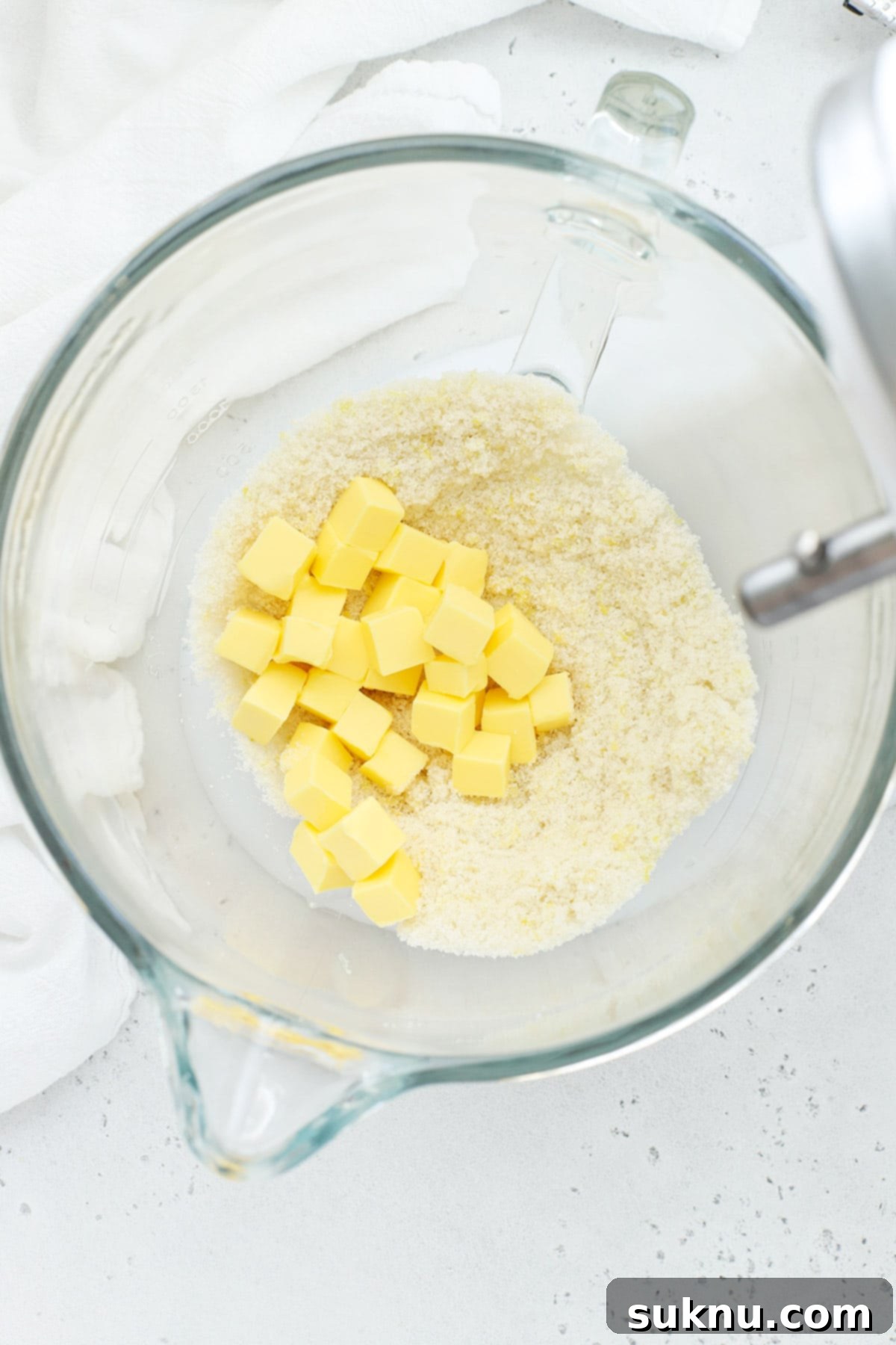 Softened butter being added to the lemon-infused sugar in a stand mixer bowl, ready for creaming.