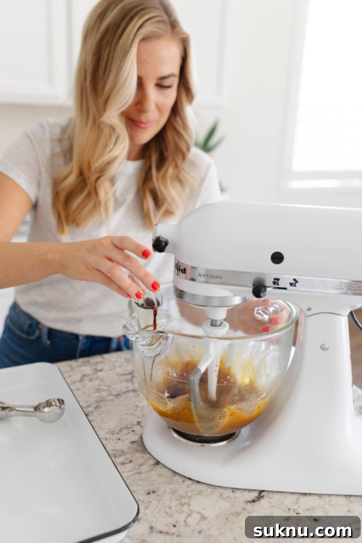Adding vanilla to a mixer with cookie batter. Scraper beater attachment is running