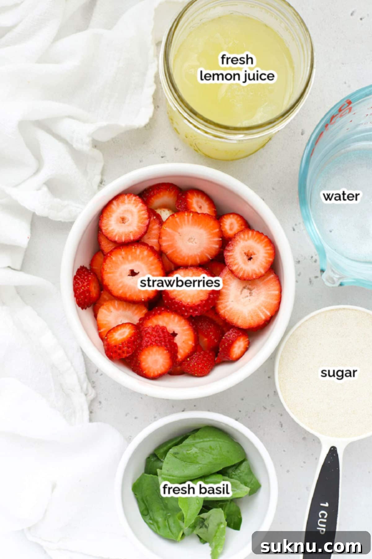 Strawberry Basil Bliss Lemonade 3 Arrangement of fresh strawberries, lemons, basil leaves, sugar, and a pitcher, showcasing the core ingredients for strawberry basil lemonade.