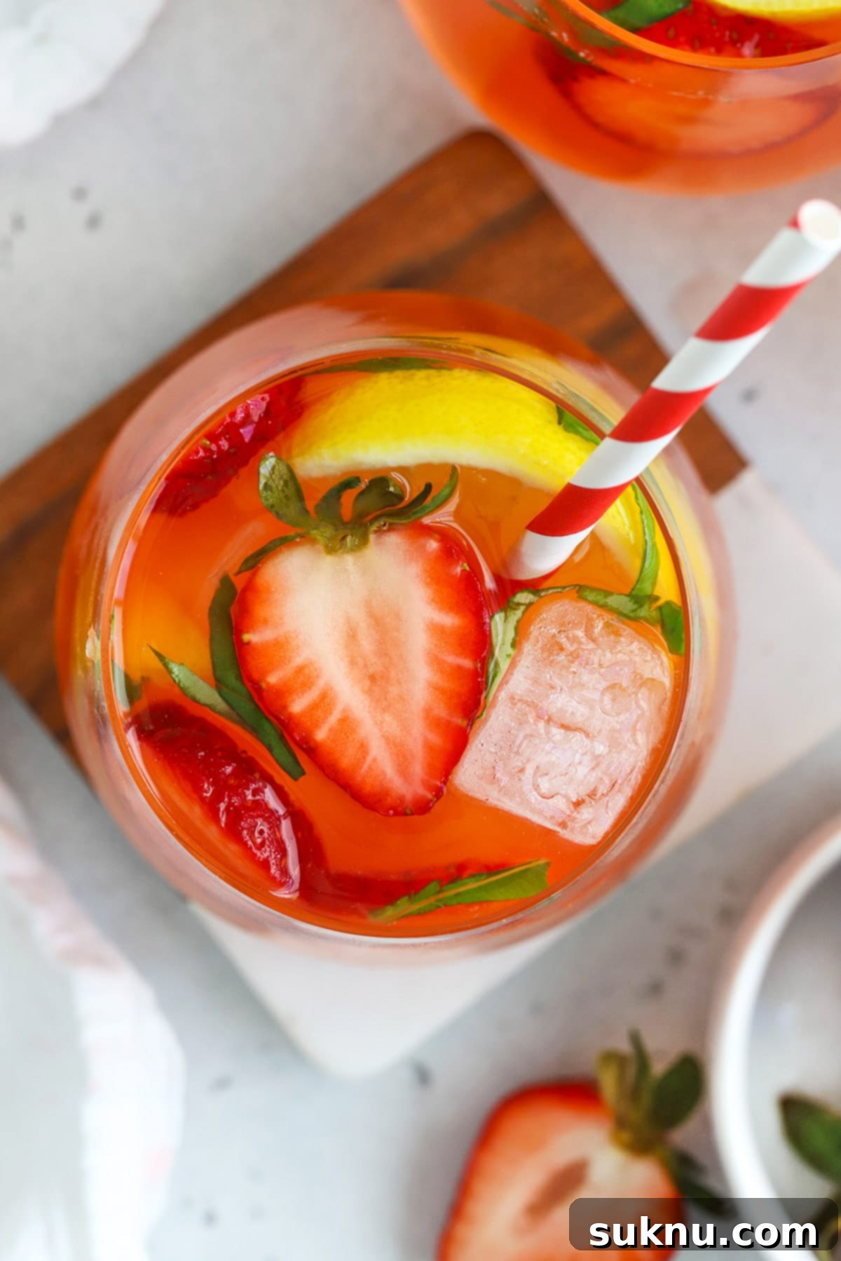 Strawberry Basil Bliss Lemonade 5 Overhead view of a beautifully garnished glass of homemade strawberry basil lemonade with lemon slices, fresh strawberries, and basil leaves.
