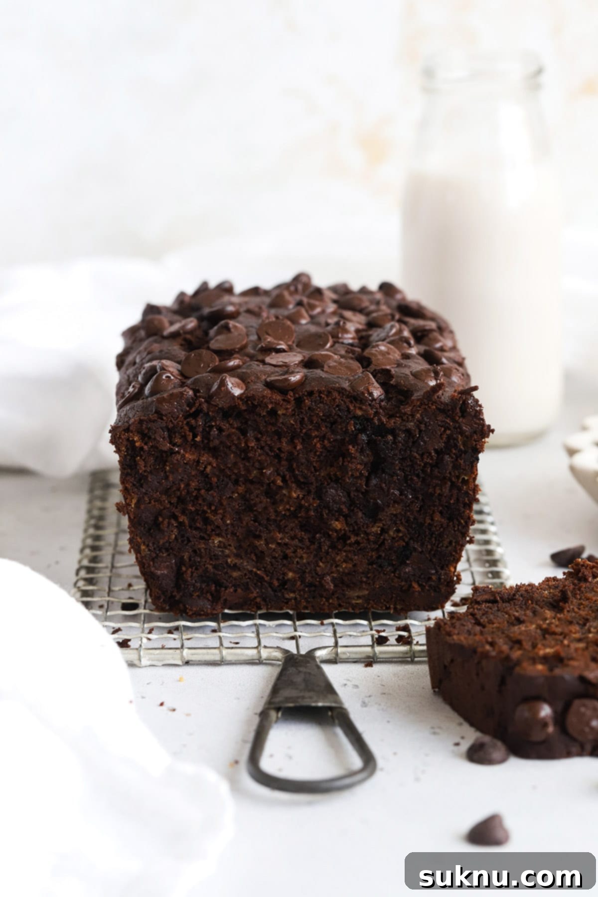 Decadent Gluten-Free Chocolate Banana Bread 2 Front view of a beautifully baked loaf of one-bowl gluten-free chocolate chocolate chip banana bread, showcasing its rich brown color and melted chocolate chips on top.