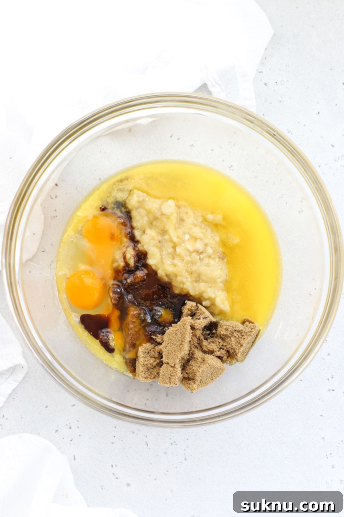 Decadent Gluten-Free Chocolate Banana Bread 5 Close-up of the initial mixing stage, showing mashed bananas, melted butter, brown sugar, eggs, and vanilla being vigorously whisked together in a spacious bowl, creating a smooth, golden wet mixture for the gluten-free chocolate banana bread.