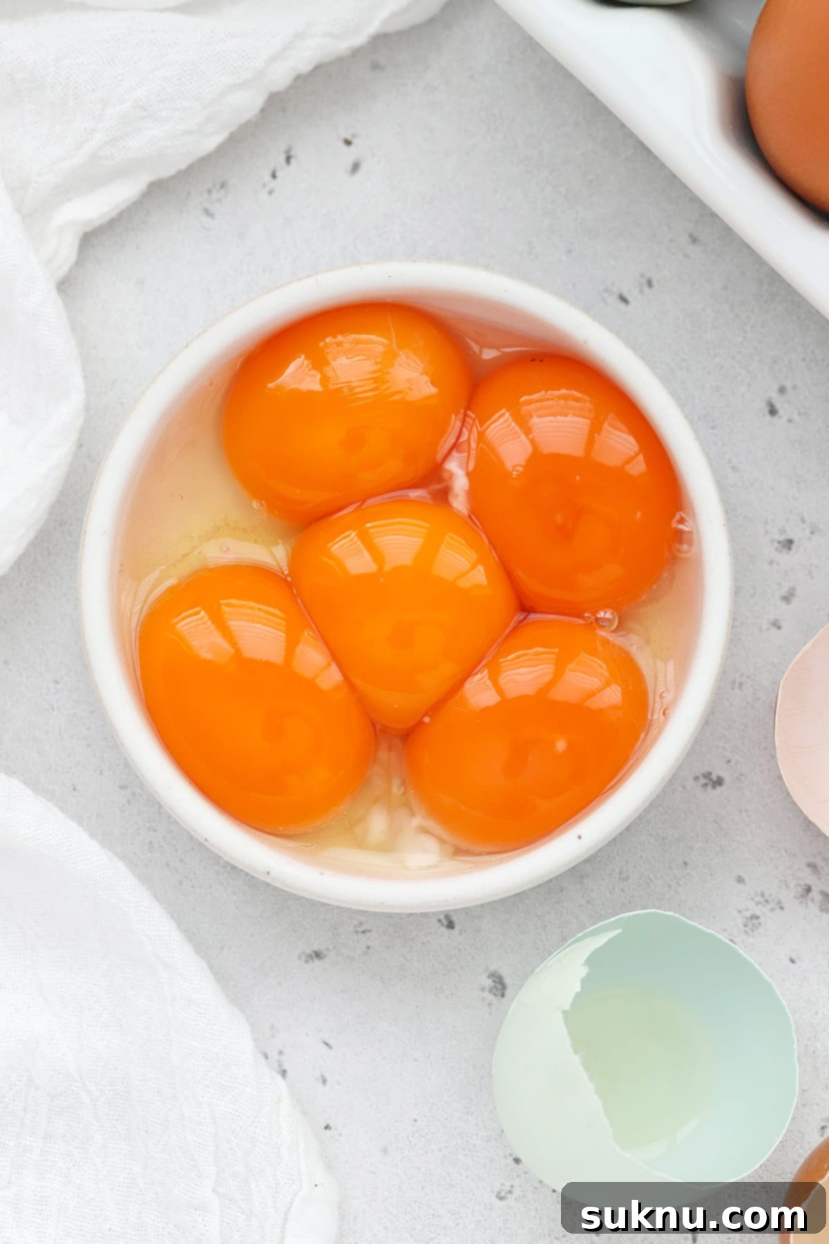 Unlock Room Temperature Eggs in Minutes 8 Overhead view of egg yolks in a small white bowl, ready for a recipe.