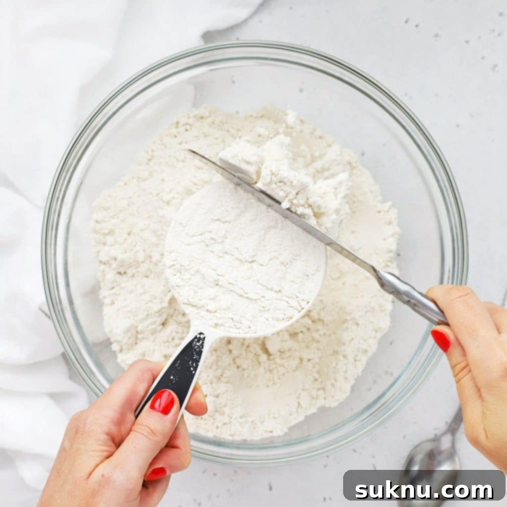 Overhead view of someone using the scoop and level method to measure flour correctly.