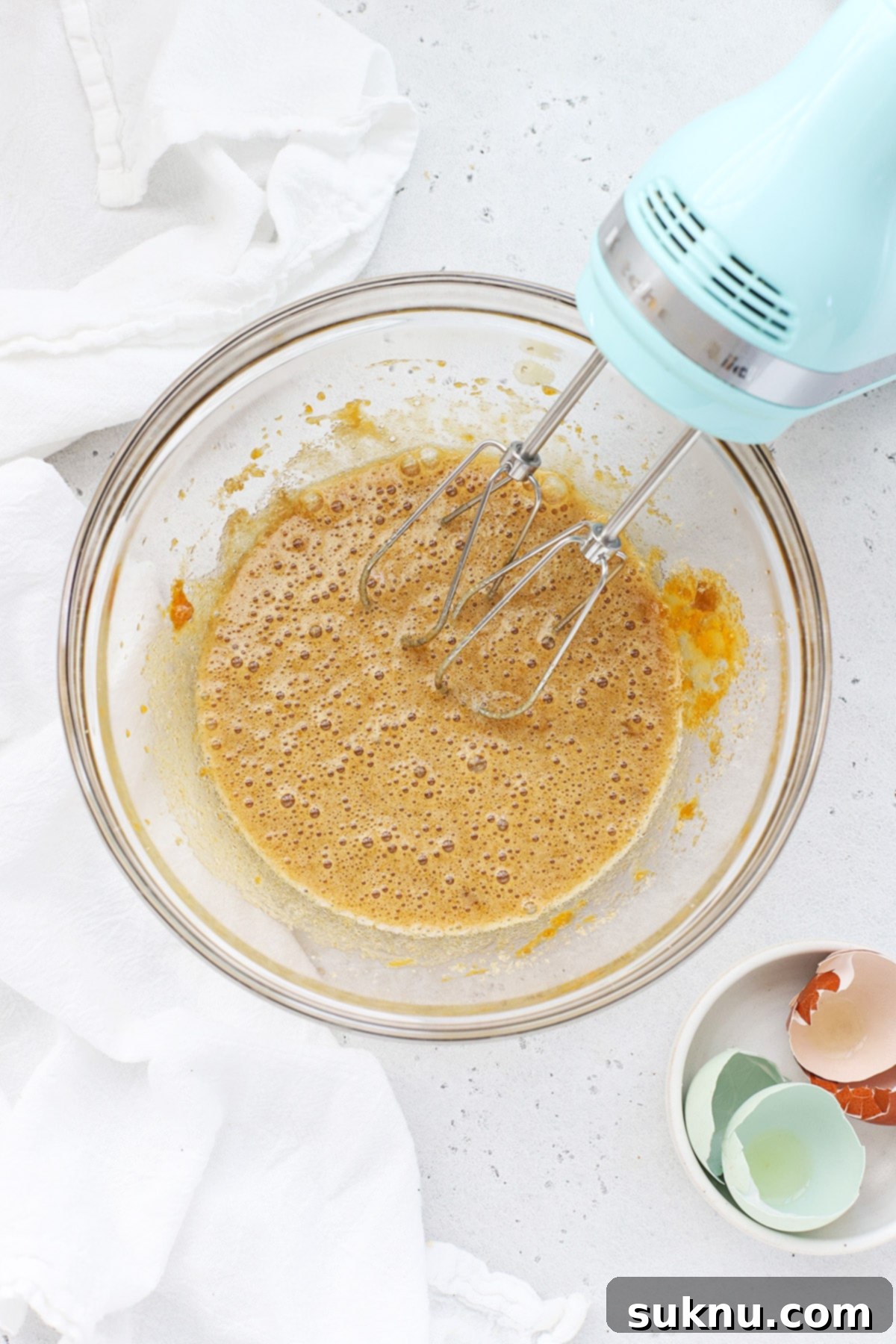 Whisking brown sugar and white sugar with eggs in a large bowl to make brownie cookies.