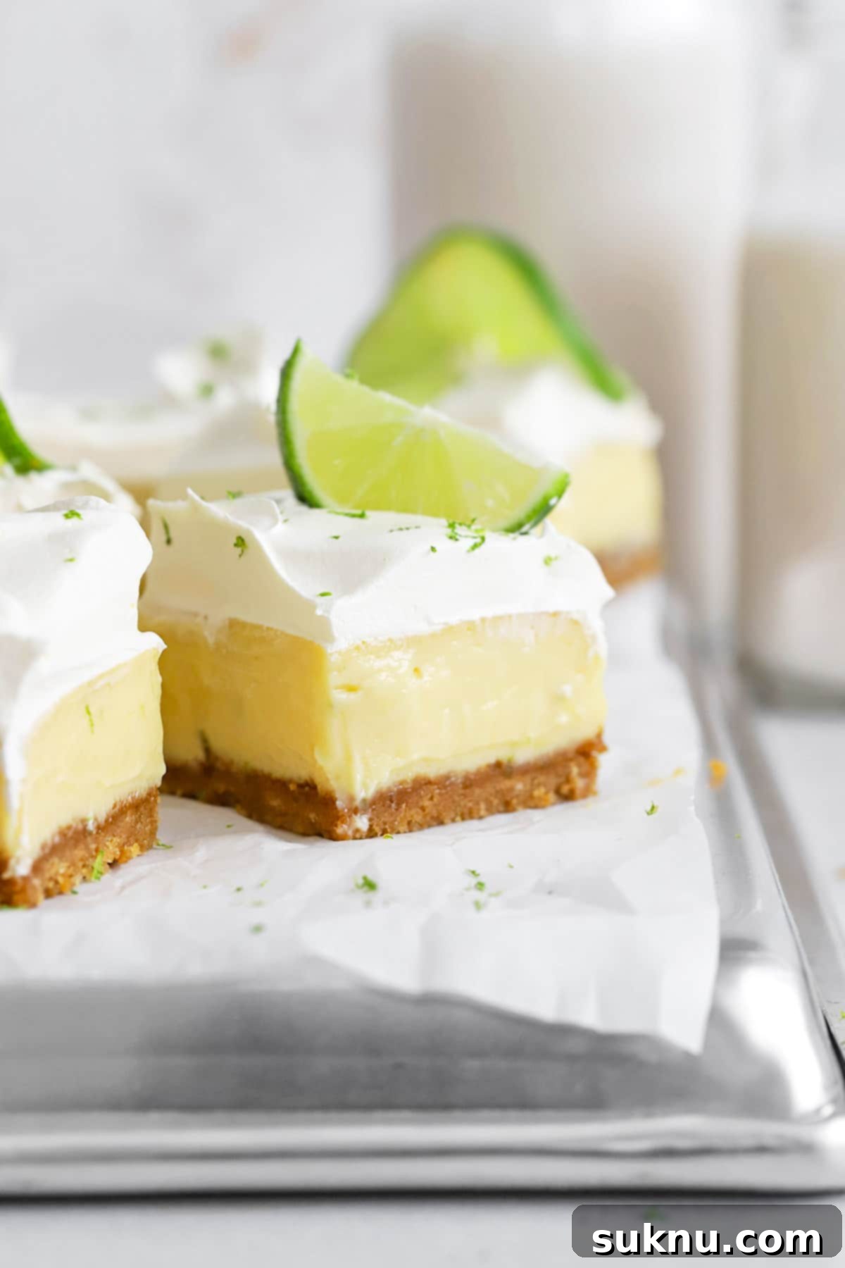 Front view of gluten-free key lime pie bars with graham cracker crust, garnished with lime and whipped cream