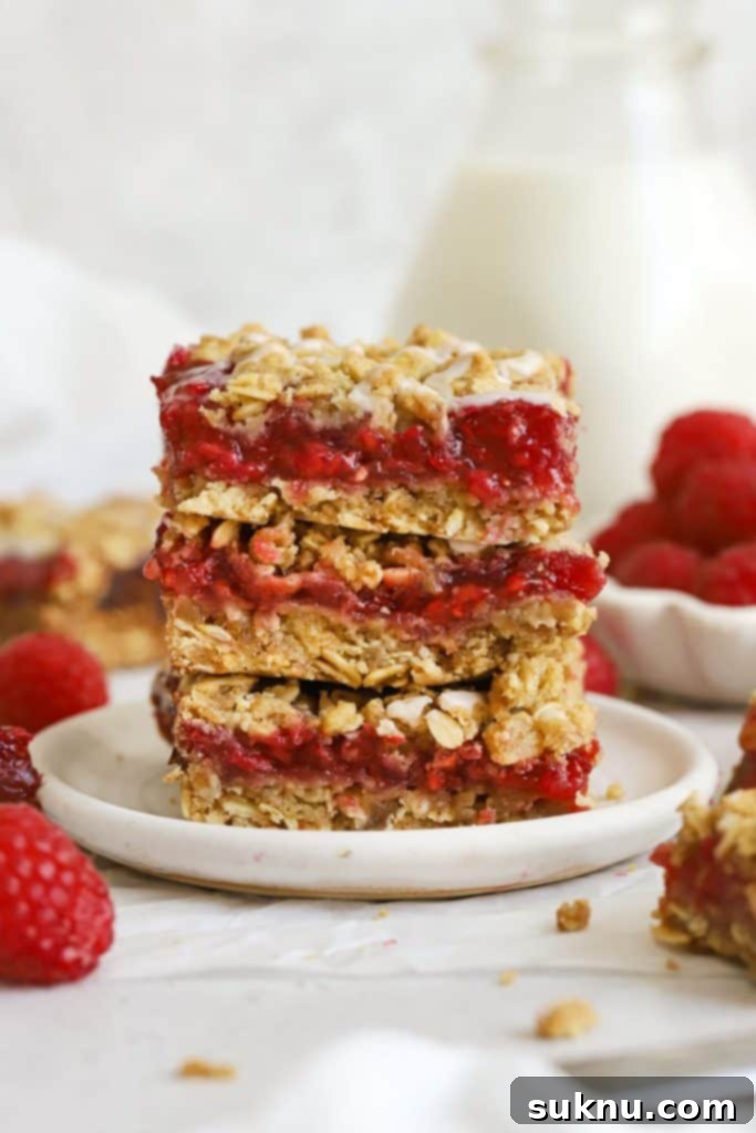 three gluten-free raspberry crumble bars stacked on a white plate