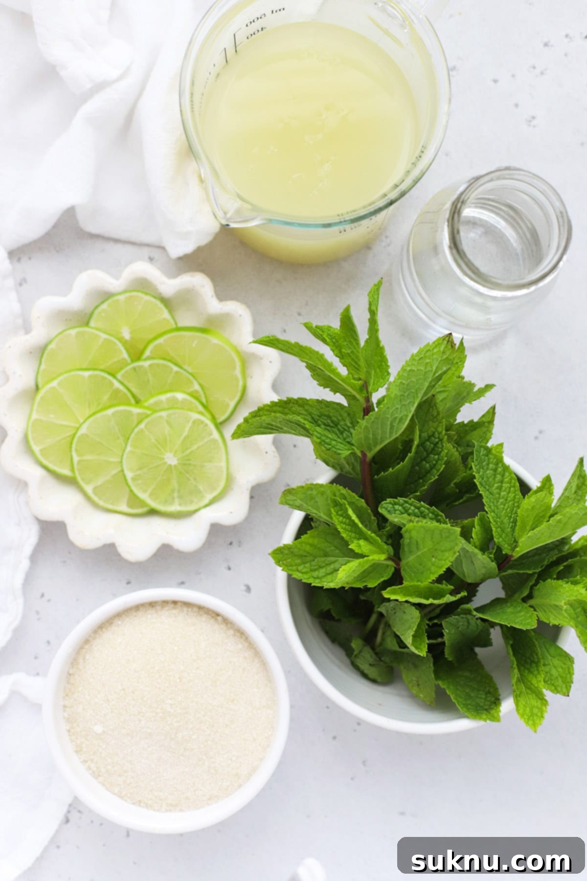 Zesty Mint Lime Mocktail 3 Overhead view of fresh limes, mint leaves, and a glass pitcher, essential ingredients for homemade virgin mojito mint limeade.