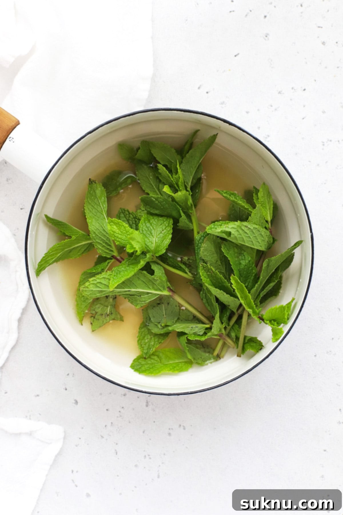 Zesty Mint Lime Mocktail 4 Close-up of sugar, water, and fresh mint leaves combined in a saucepan, ready to be simmered for mint simple syrup.