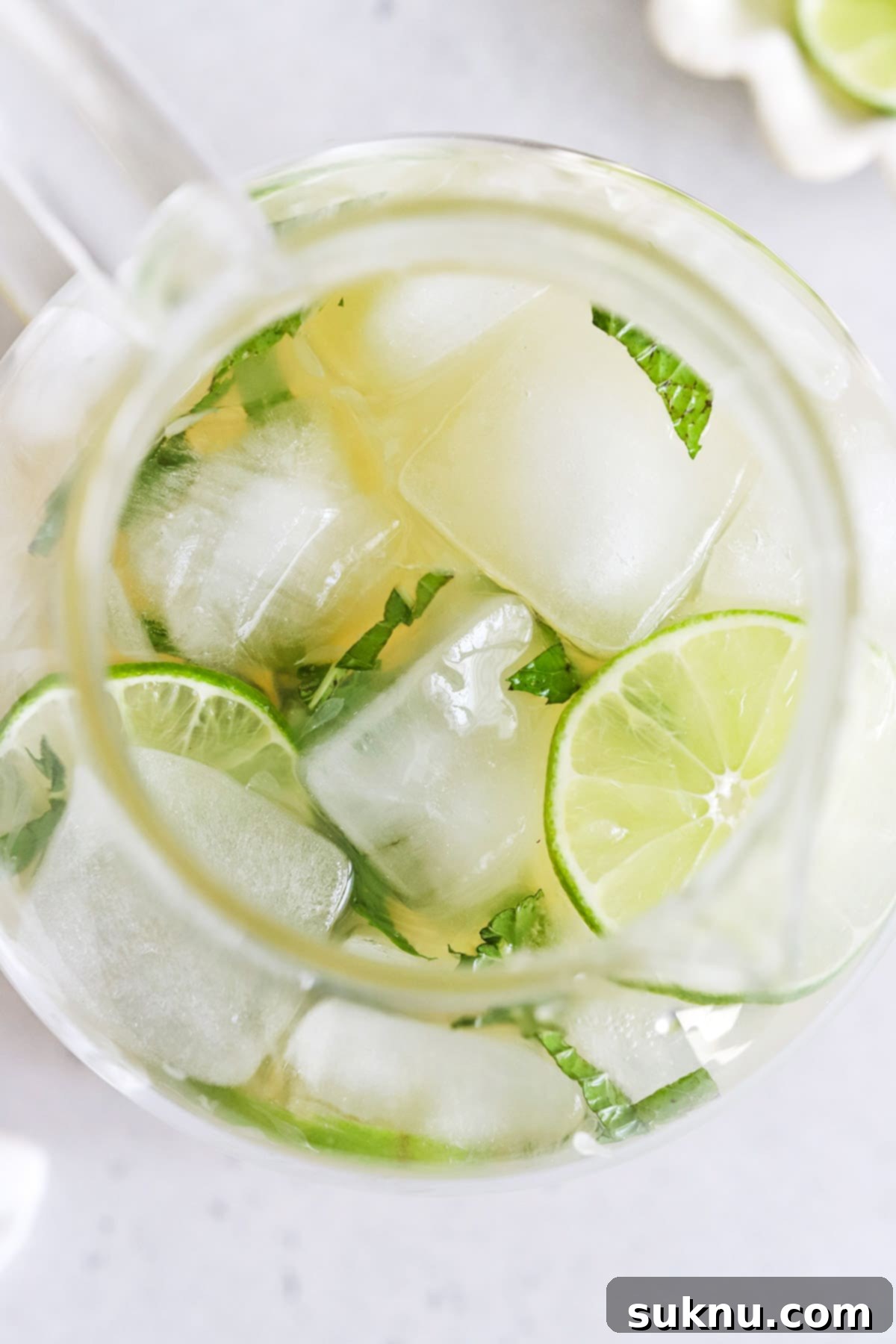 Zesty Mint Lime Mocktail 9 Overhead view of a glass pitcher filled with virgin mojito mint limeade, garnished with fresh mint sprigs and lime slices.
