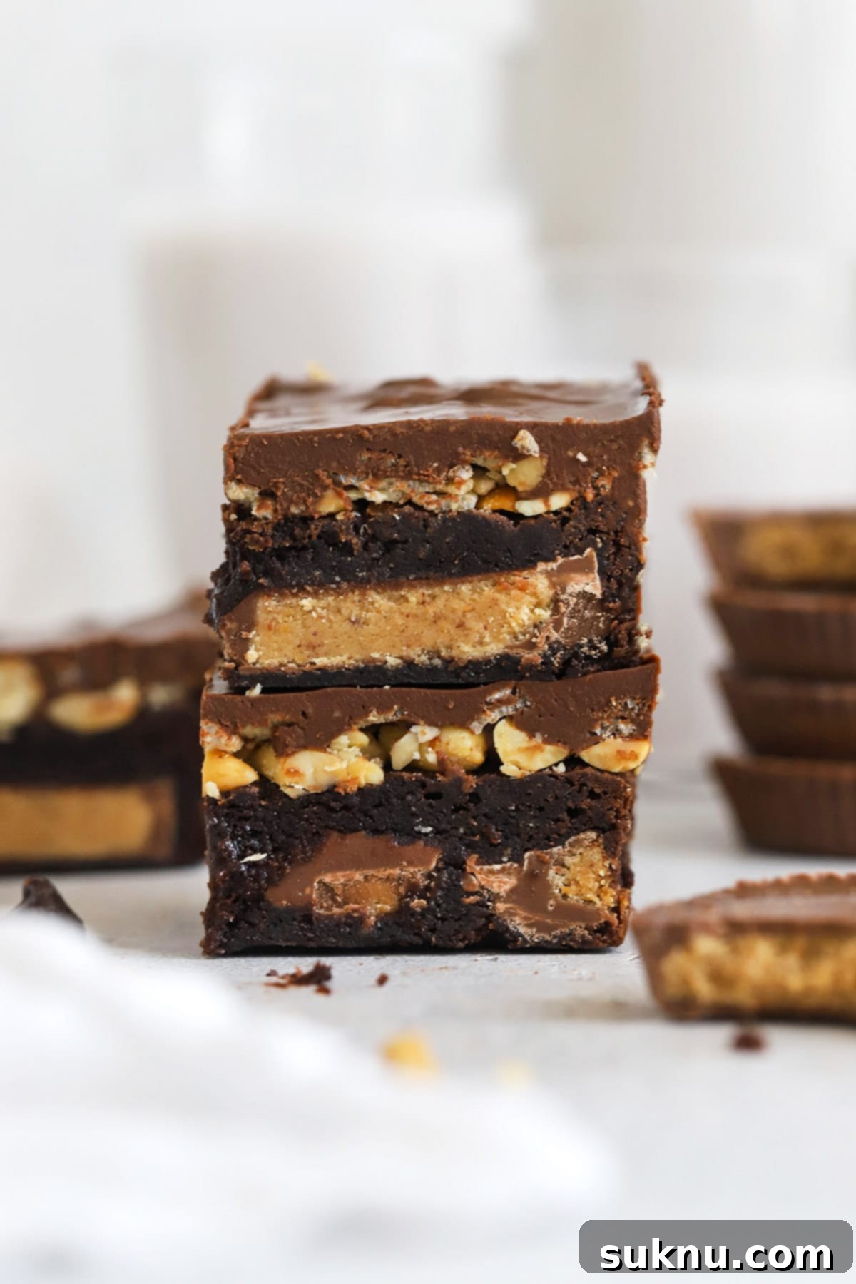 Front view of several stacked gluten-free peanut butter cup brownies, showcasing the fudgy base and crispy topping.