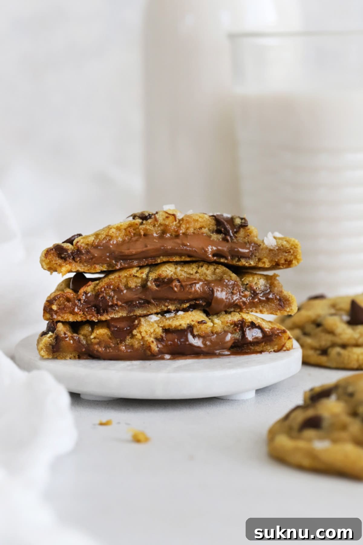 Halved gluten-free Nutella stuffed chocolate chip cookies, stacked artfully, showing their perfect golden-brown exterior and irresistible filling.