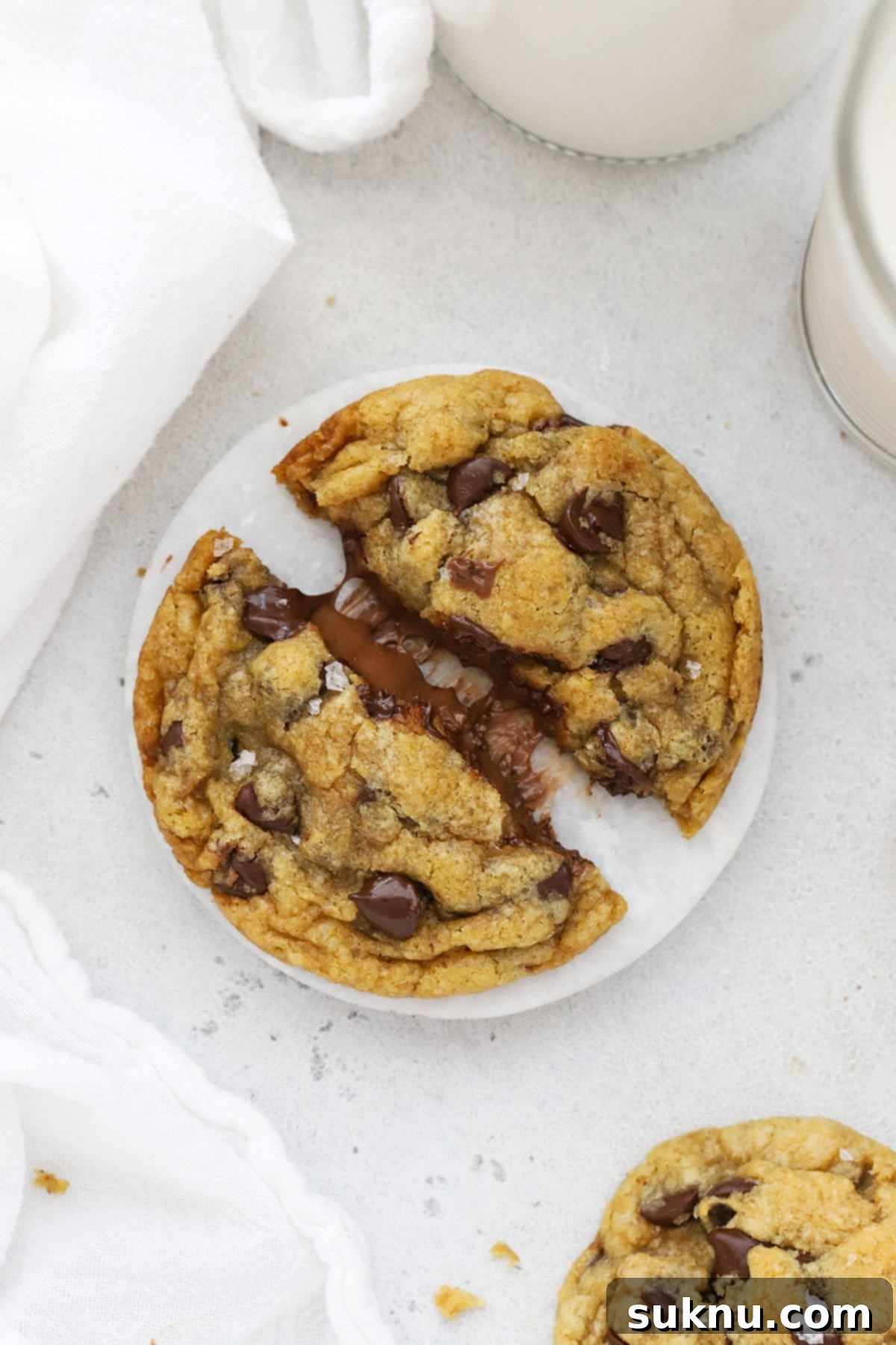A gluten-free Nutella stuffed chocolate chip cookie being gently pulled apart, revealing its warm, molten Nutella center and chewy texture.