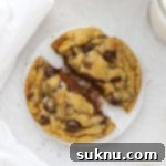 Gluten-free Nutella stuffed chocolate chip cookie being pulled apart to reveal the gooey nutella center
