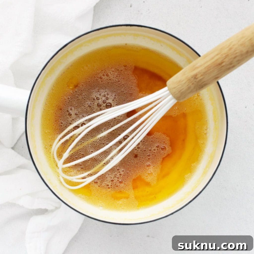 A close-up image showing how to make brown butter, with the butter slowly browning in a saucepan, demonstrating a key step for flavorful cookies.