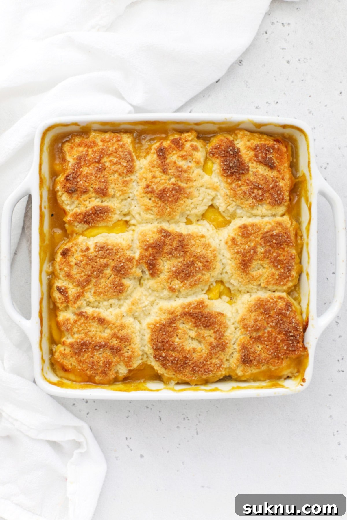 Simple Delicious Gluten-Free Peach Cobbler 9 A glorious, freshly baked gluten-free peach cobbler emerging from the oven, featuring a perfectly golden-brown biscuit topping and visibly bubbling peach filling.