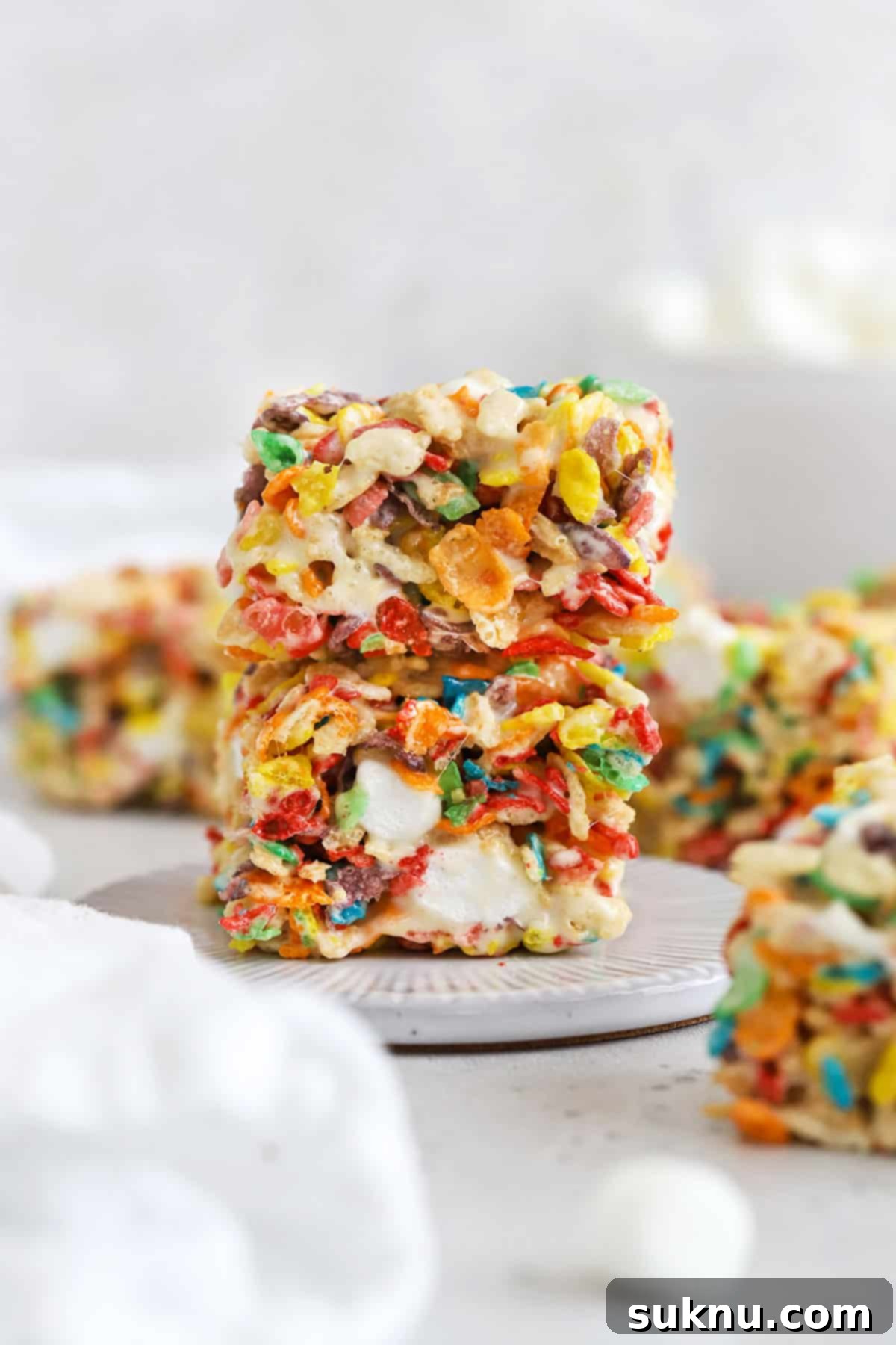 Gluten-Free Fruity Pebbles Treats 2 Two vibrant gluten-free Fruity Pebbles treats stacked on a white dessert plate, showcasing their colorful appeal and delicious texture.