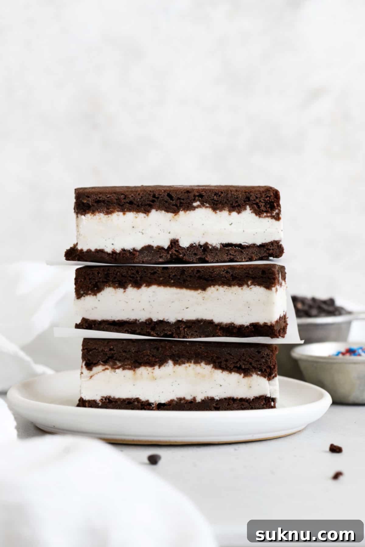 three gluten-free brownie ice cream sandwiches stacked on a white plate