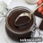 Dipping a spoon into a jar of homemade chocolate syrup