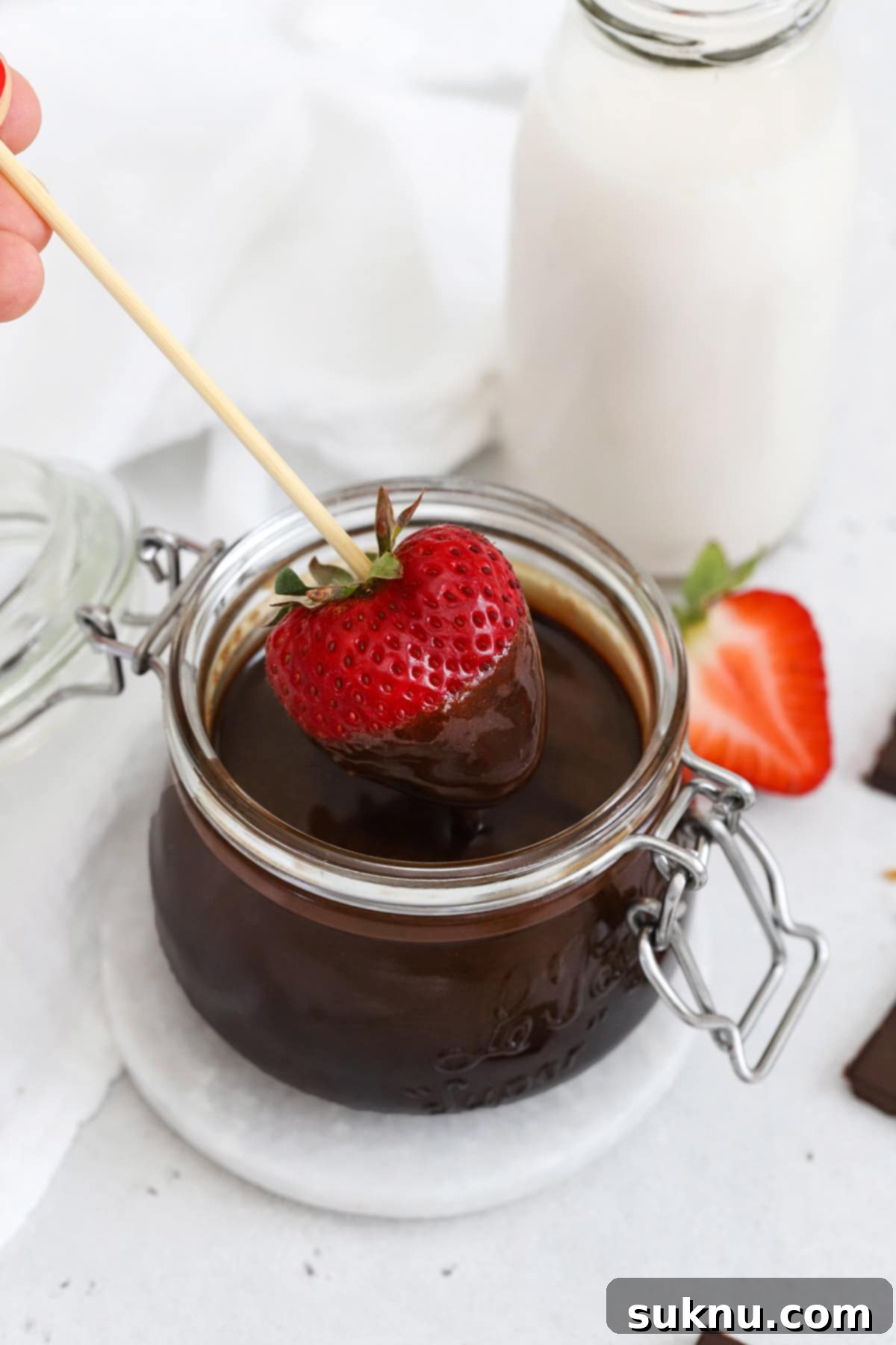 Dipping strawberries into a jar of homemade chocolate syrup