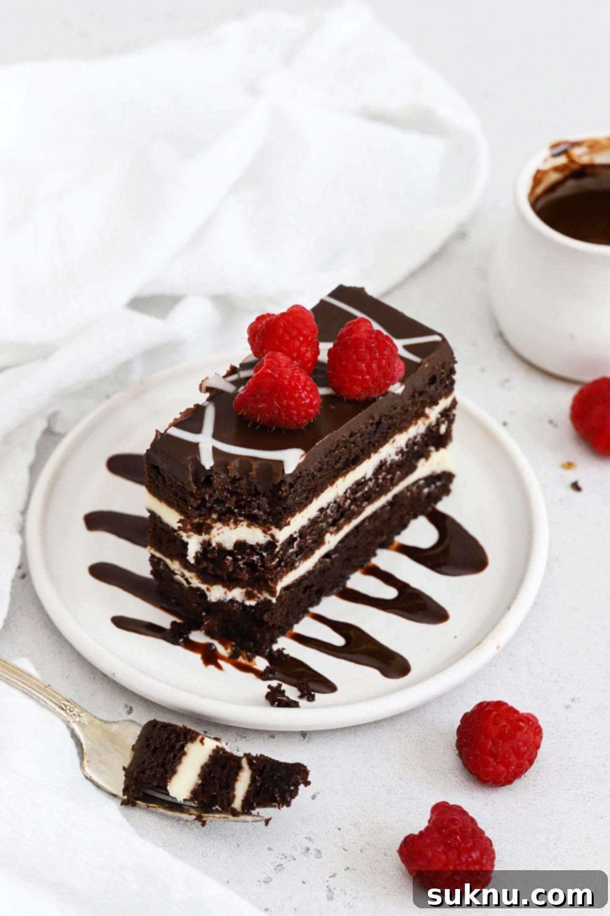 Front view of a slice of gluten-free chocolate cake on a plate drizzled with homemade chocolate syrup