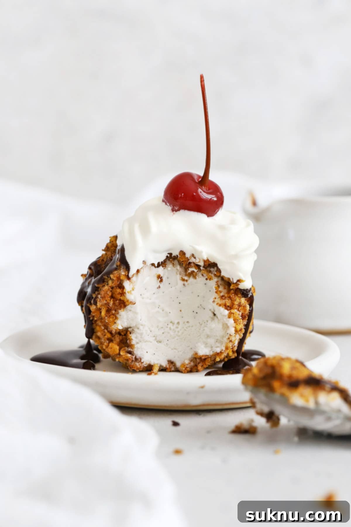 Front view of gluten-free fried ice cream with one bite scooped out of it