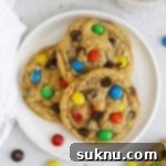 Soft & Chewy Gluten-Free M&M Cookies 11 Overhead view of three gluten-free M&M cookies on a plate, showcasing their soft texture and colorful candies