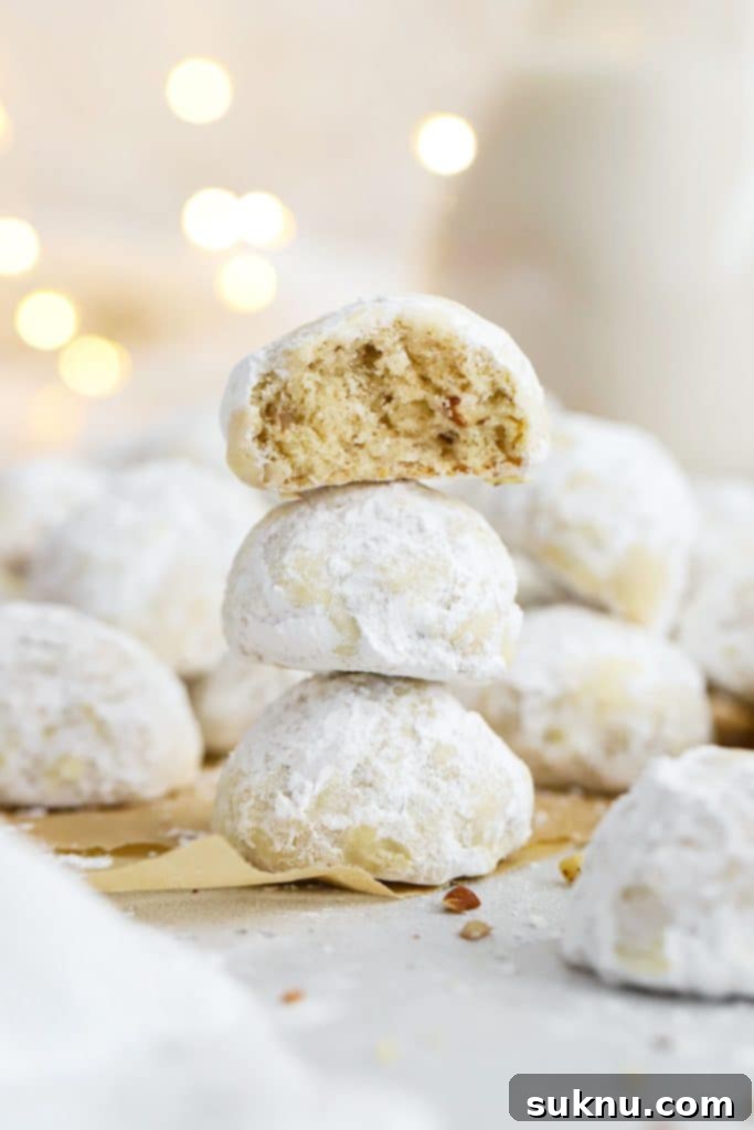 Soft & Chewy Gluten-Free M&M Cookies 8 gluten-free snowball cookies stacked in a column, dusted with powdered sugar