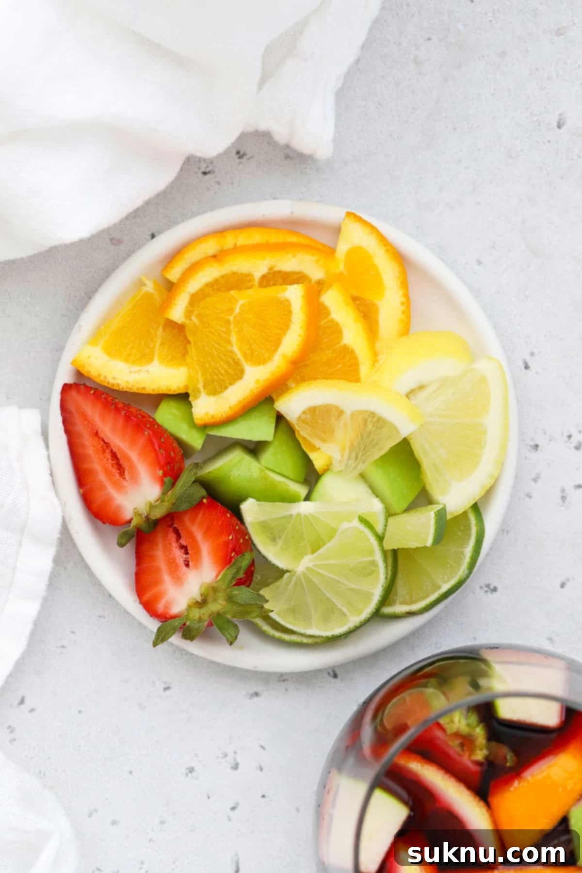Overhead view of chopped fresh fruit, including oranges, green apples, and strawberries, prepared for non-alcoholic sangria
