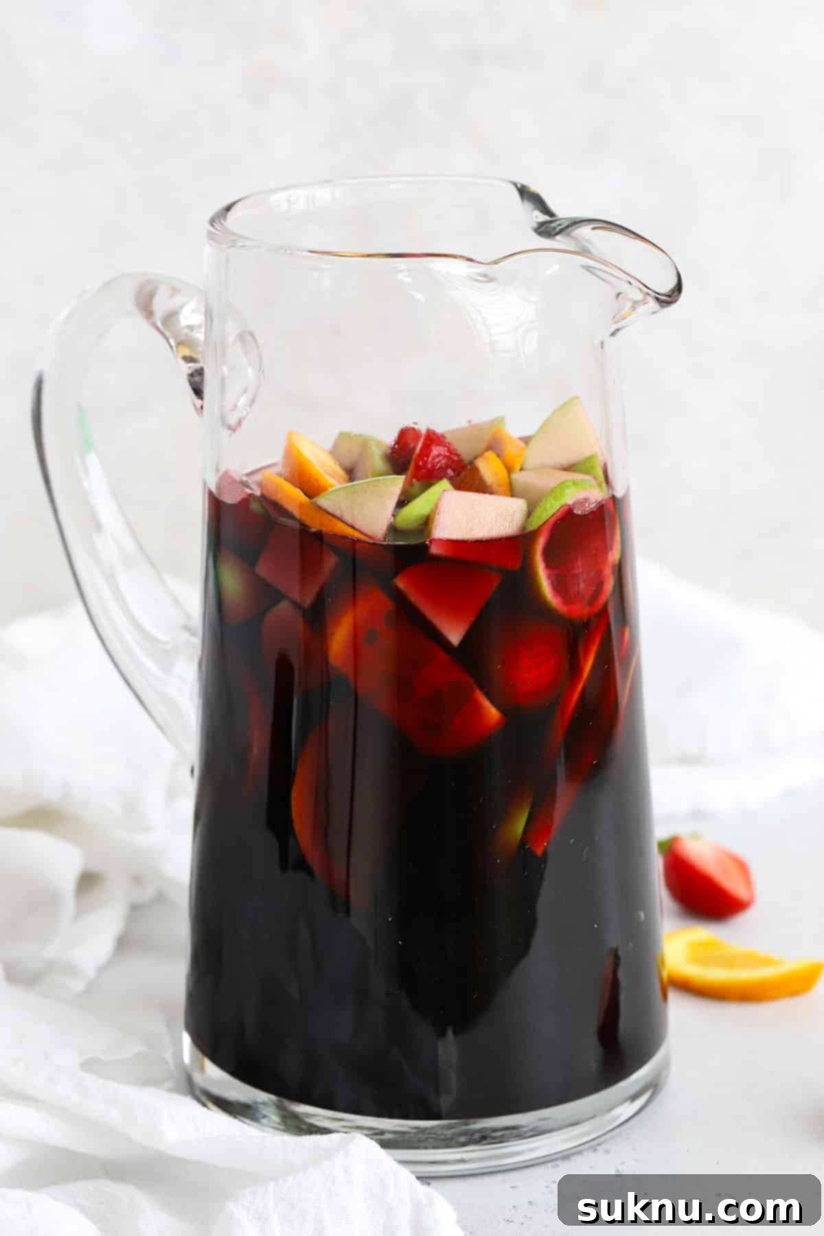 A large glass pitcher filled with vibrant non-alcoholic sangria, showcasing colorful fruit slices