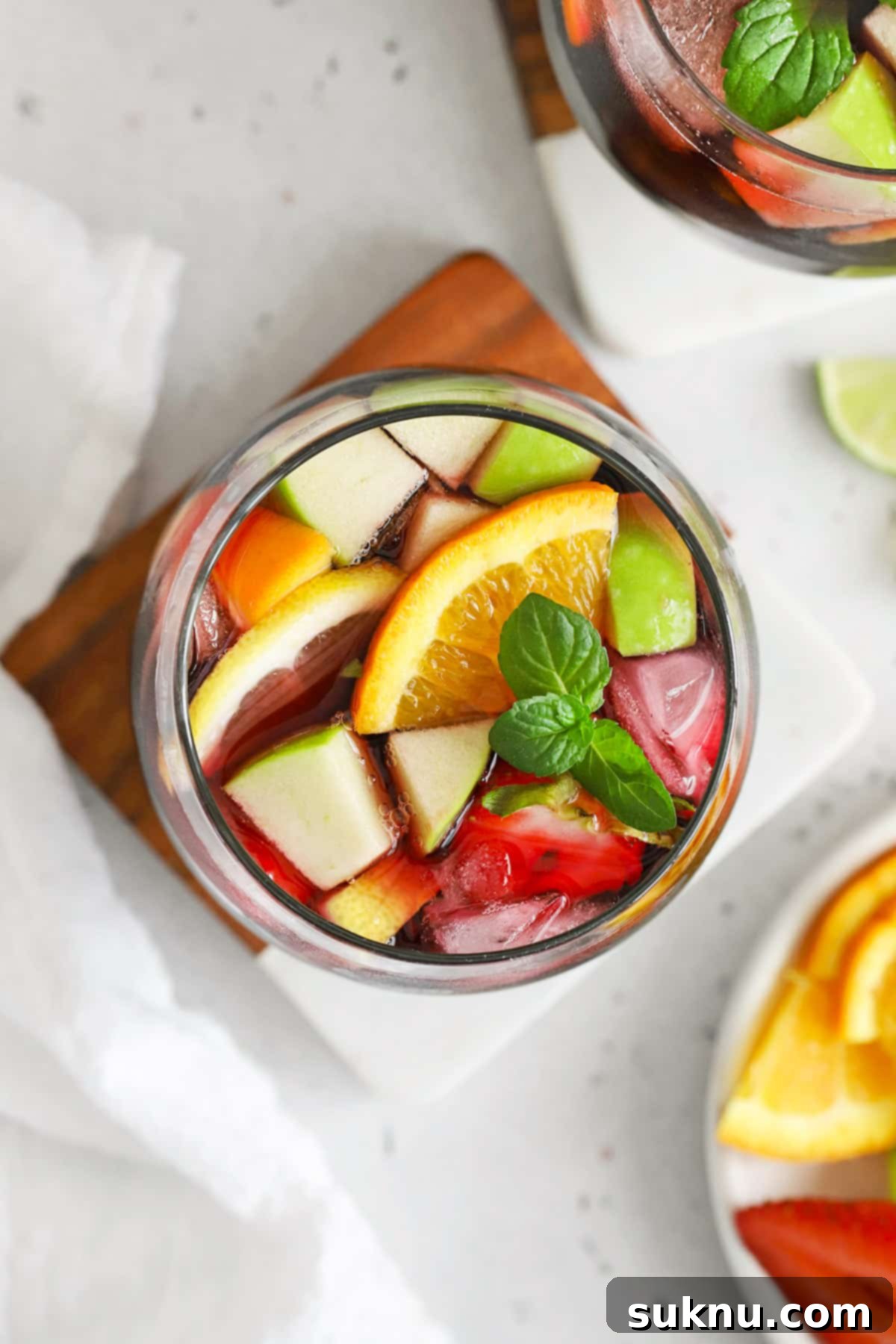 Overhead view of a single glass of non-alcoholic sangria, with a straw and ample fresh fruit floating in the red liquid