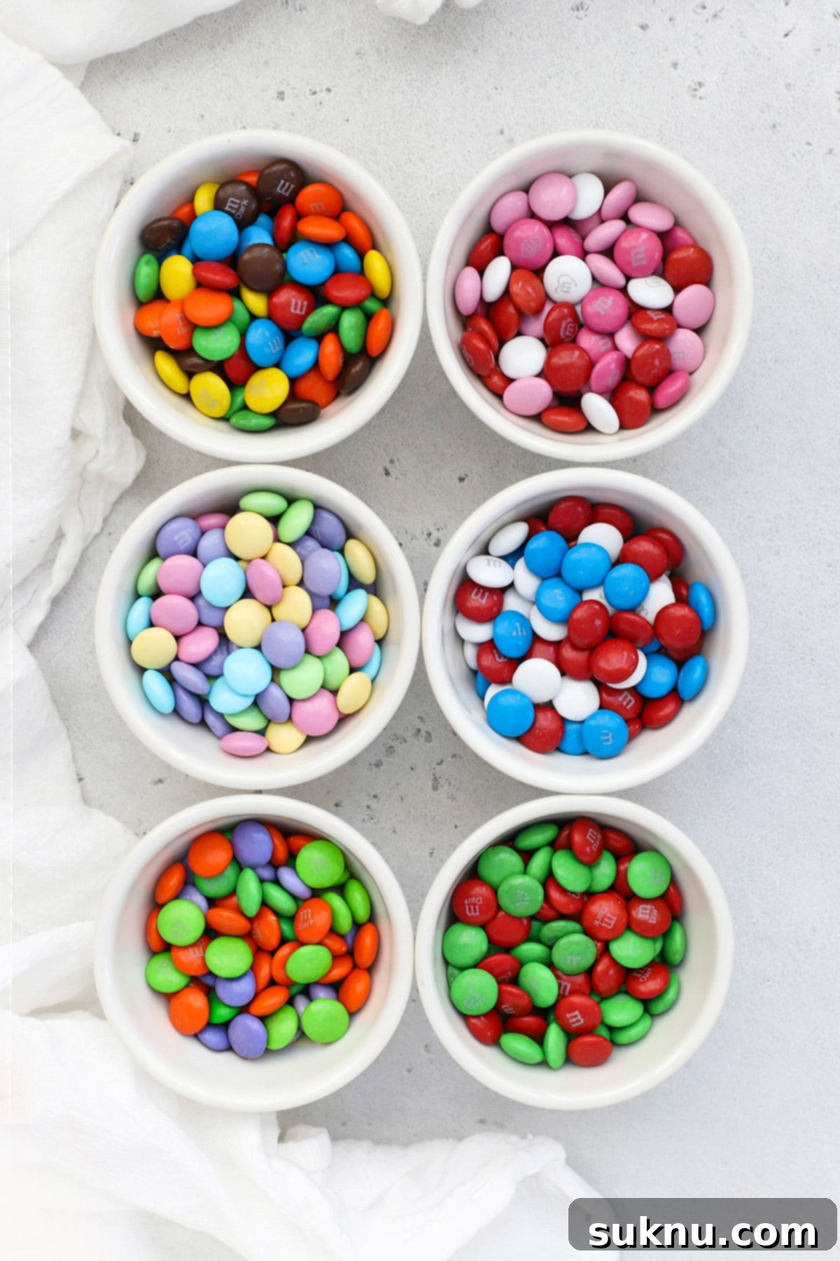 Overhead view of small bowls of holiday m&ms--original, valentine's m&ms, red white and blue m&ms, Christmas red and green m&ms, orange green and purple Halloween m&ms and pastel Easter m&ms