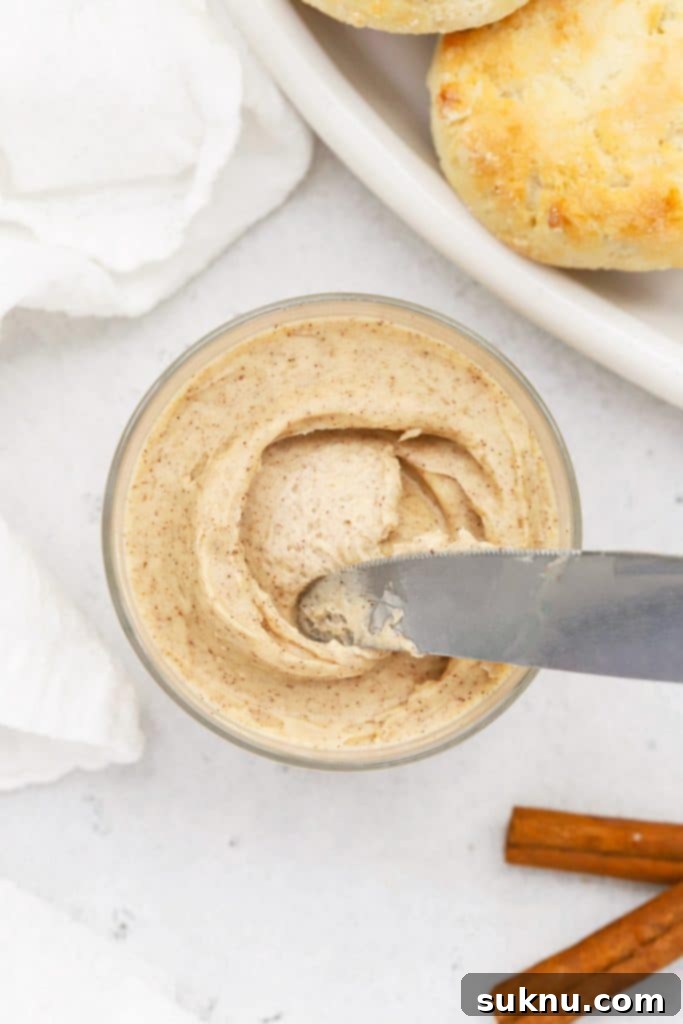Fluffy Honey Butter Made in Minutes 13 Overhead view of whipped honey butter in a small glass jar with gluten-free biscuits in the background