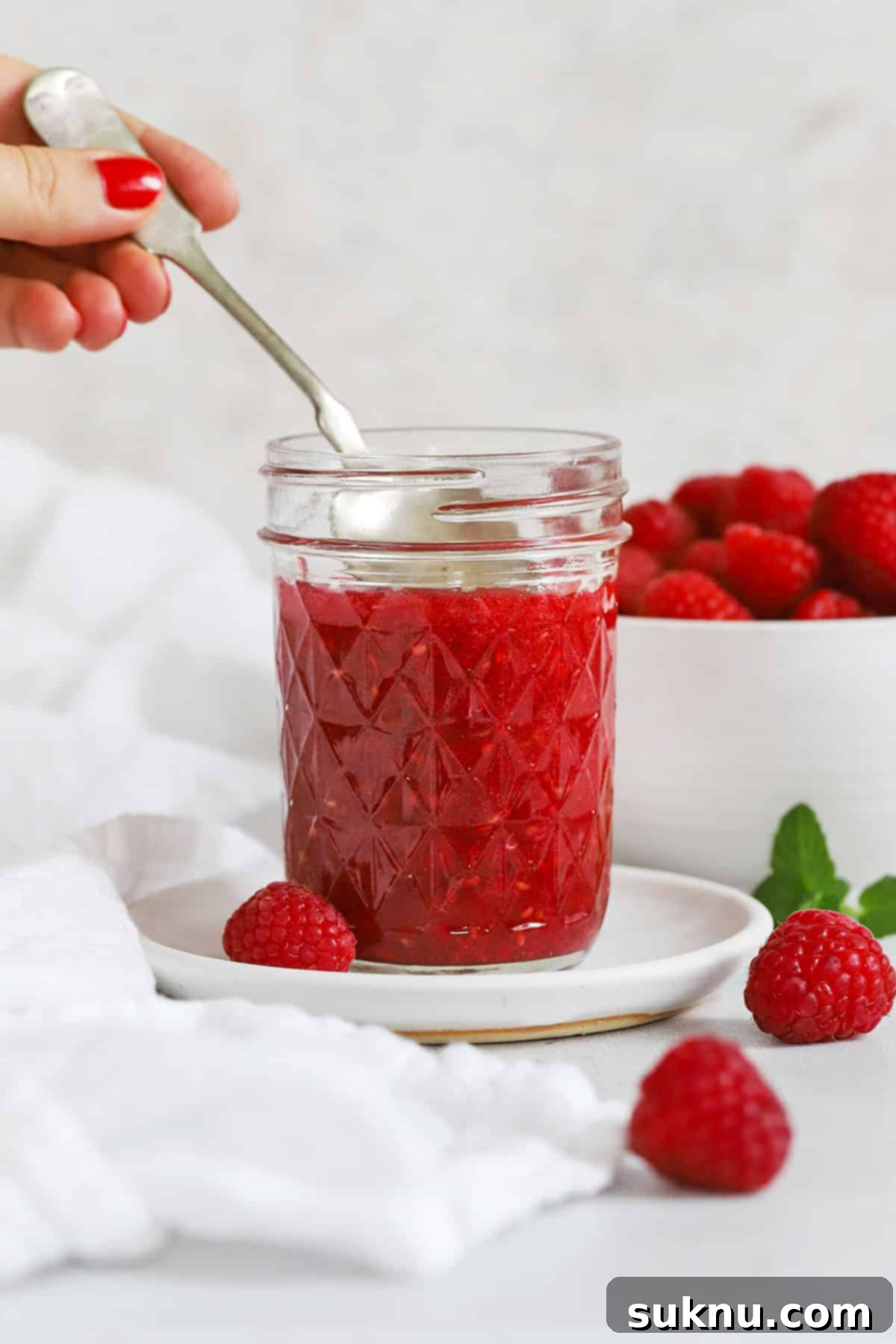 Front view of a jar of low sugar raspberry freezer jam, showcasing its vibrant color and inviting texture.