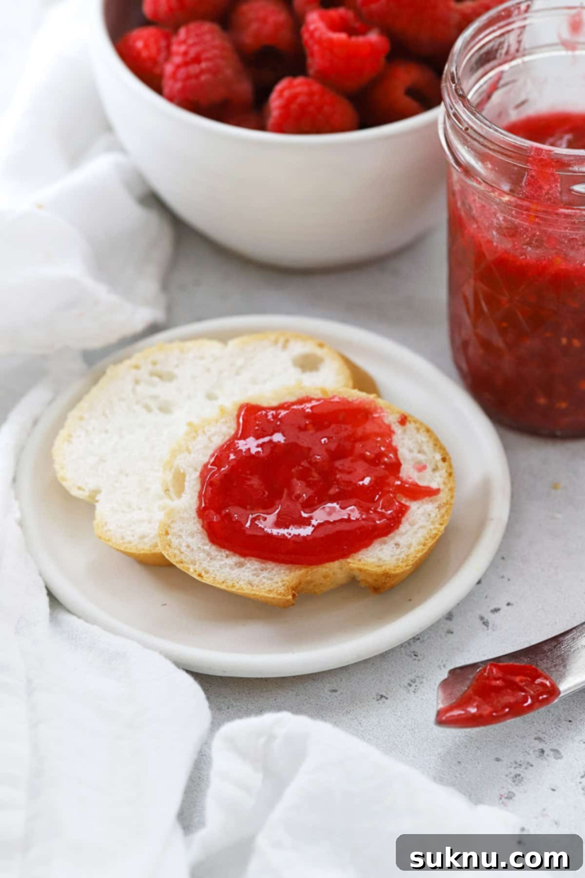 Freezer raspberry jam generously spread on a slice of gluten-free bread, ready to be enjoyed.