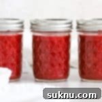Front view of three jars of easy raspberry freezer jam