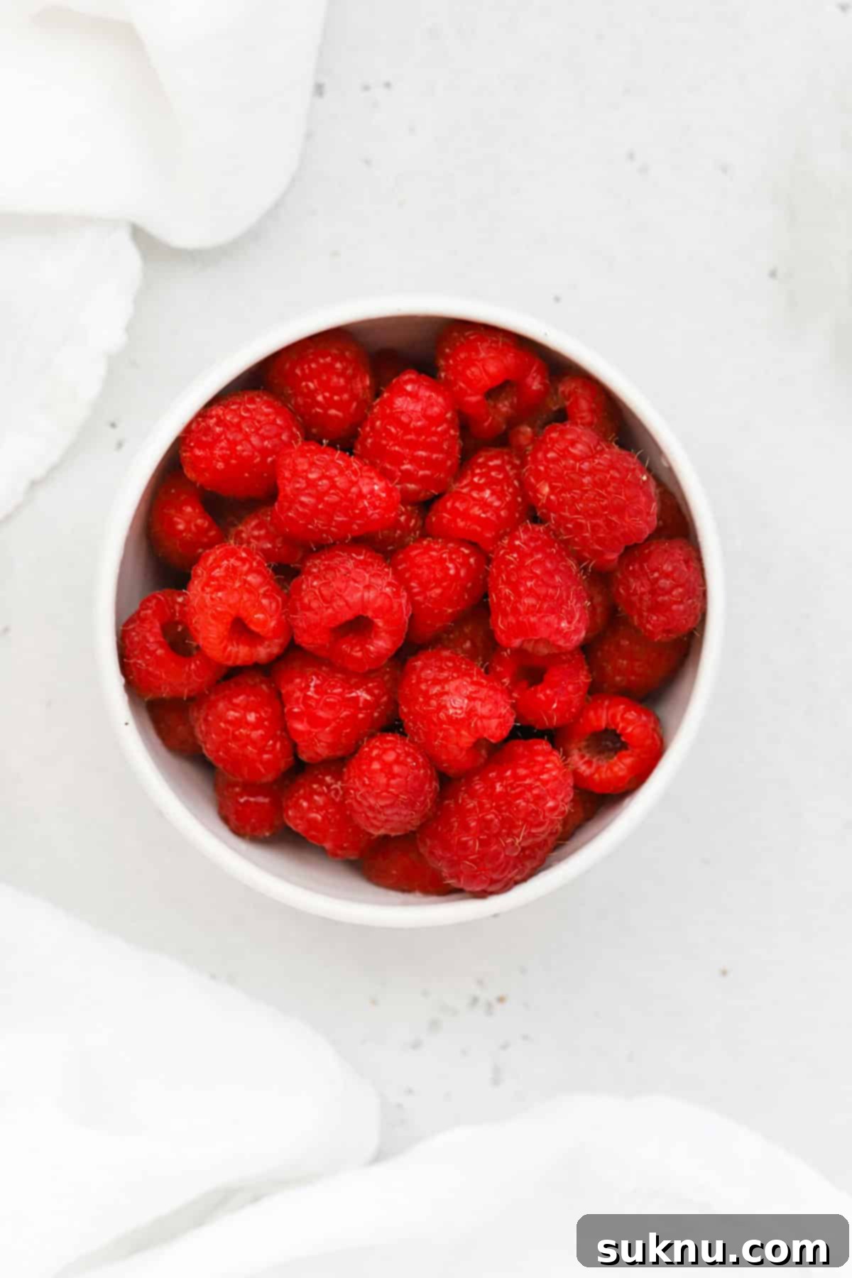 Overhead view of a bowl of red, ripe raspberries, fresh and ready for making jam.