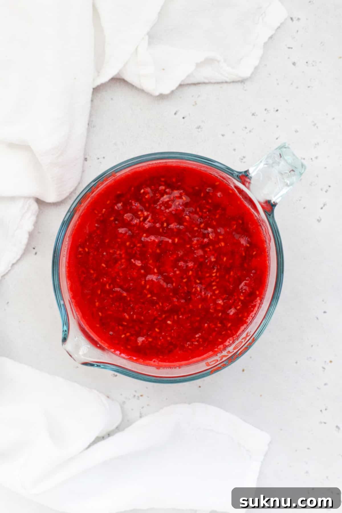 A bowl of uniformly mashed raspberries, ready for combining with other jam ingredients.