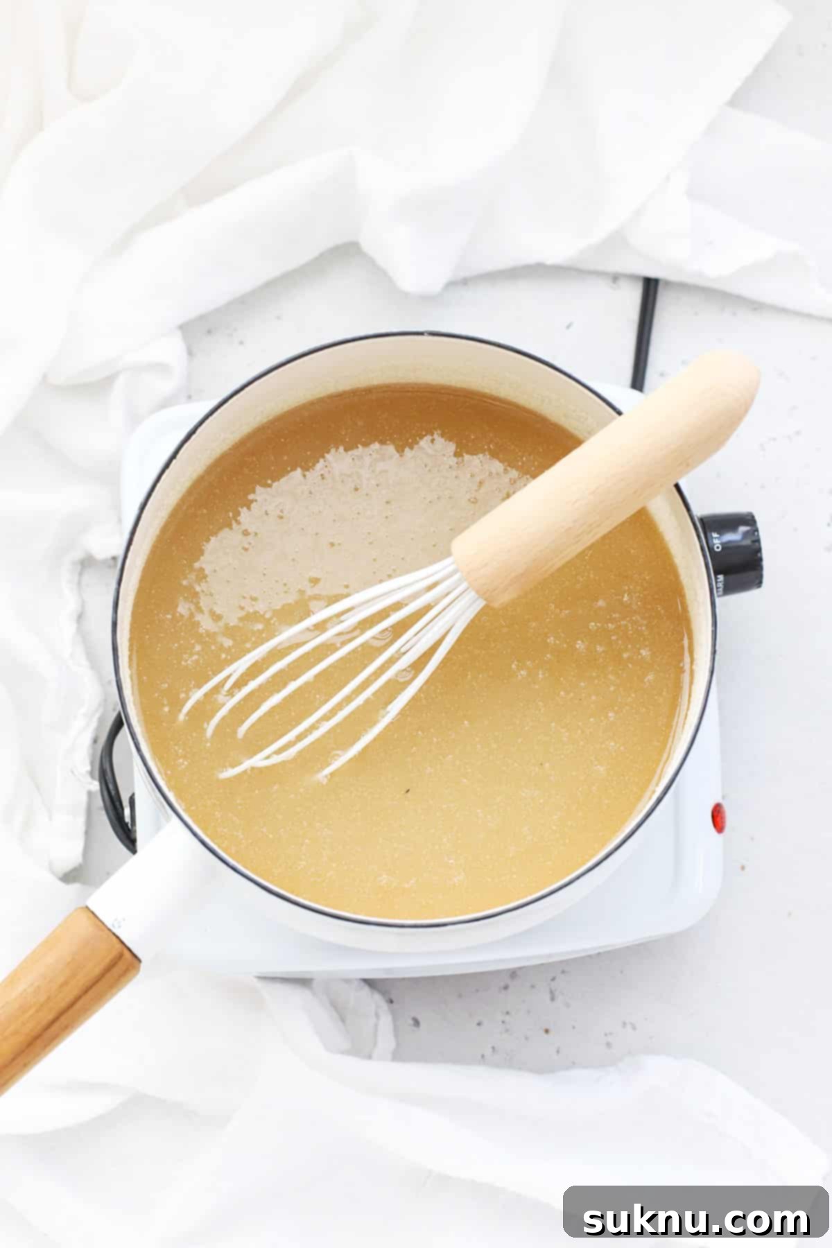 Adding water to a saucepan containing sugar and low-sugar pectin, a crucial step for low sugar raspberry freezer jam.