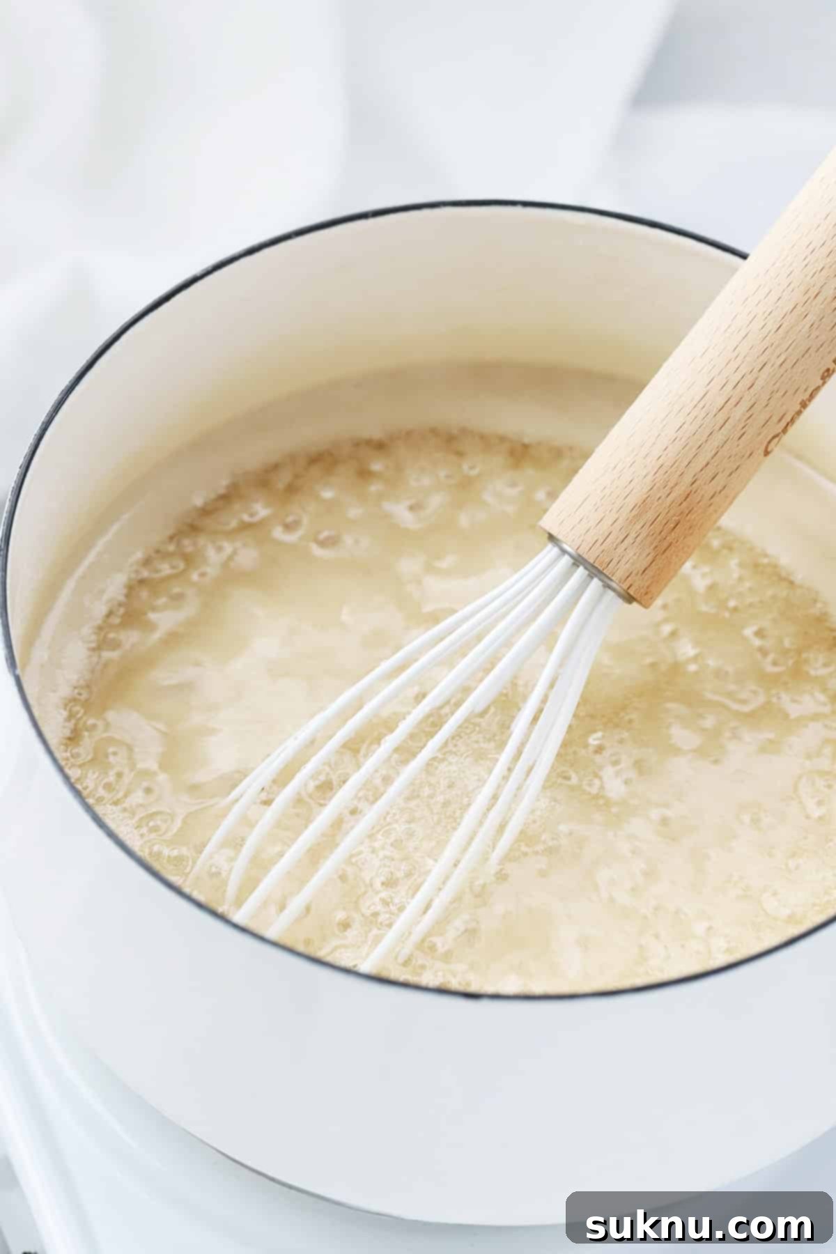 The sugar and pectin mixture boiling vigorously in a saucepan, indicating it's ready for the next step.