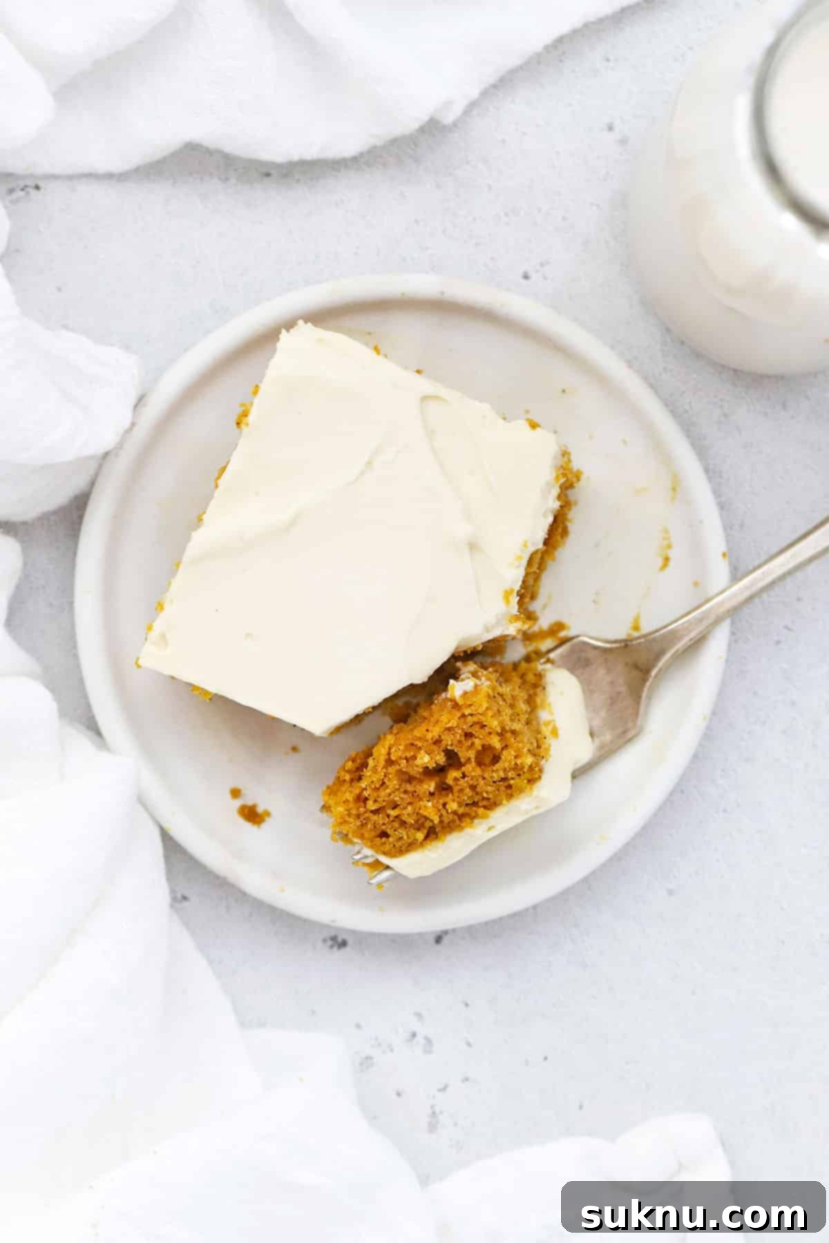 Overhead view of a single gluten-free pumpkin bar on a white plate, showcasing the frosting.