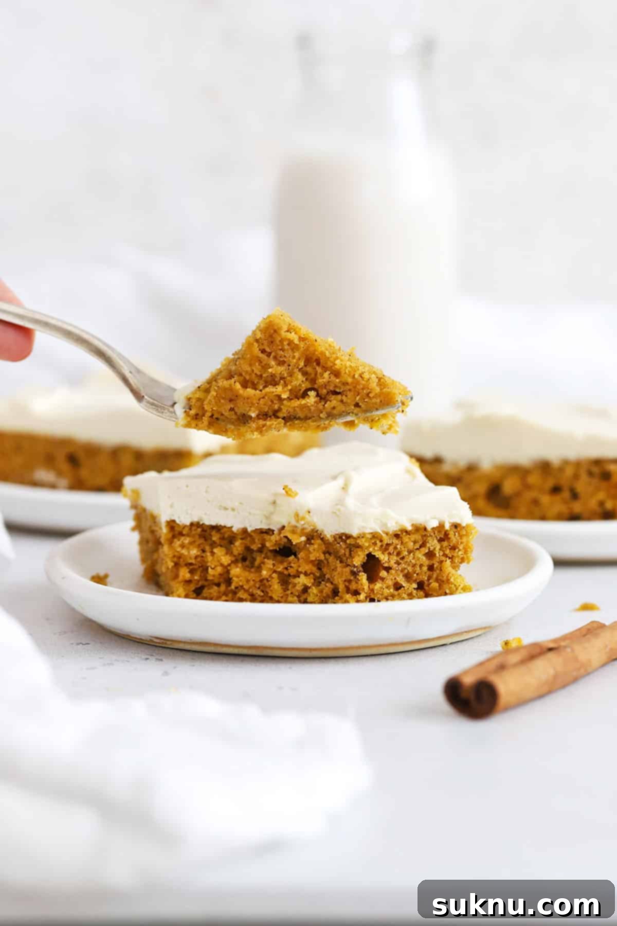 A fork taking a bite of gluten-free pumpkin bars with luscious whipped cream cheese frosting.