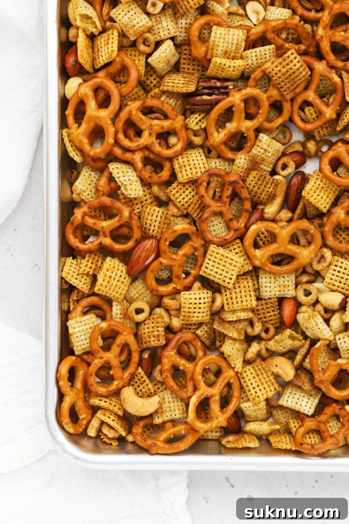 Overhead view of a baking pan filled with golden-brown, freshly baked gluten-free Chex Mix, cooling down.