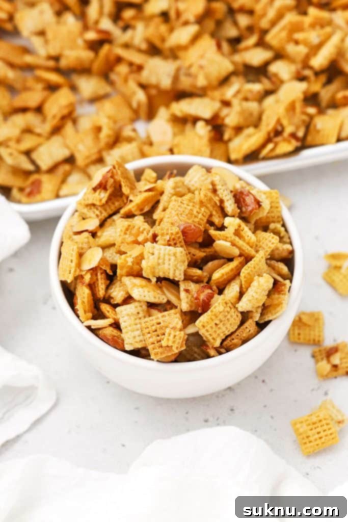 A serving bowl filled with gluten-free sweet Chex Mix featuring coconut and almonds, a delightful treat.