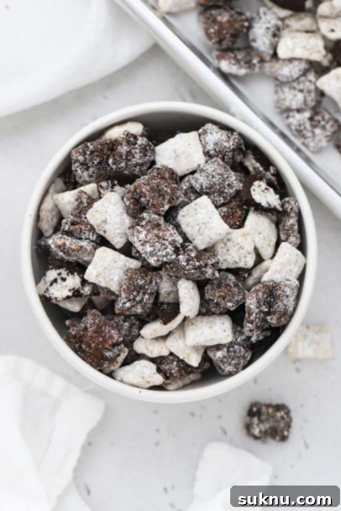 A bowl of cookies and cream muddy buddies, featuring chopped gluten-free Oreos, a rich and decadent snack.