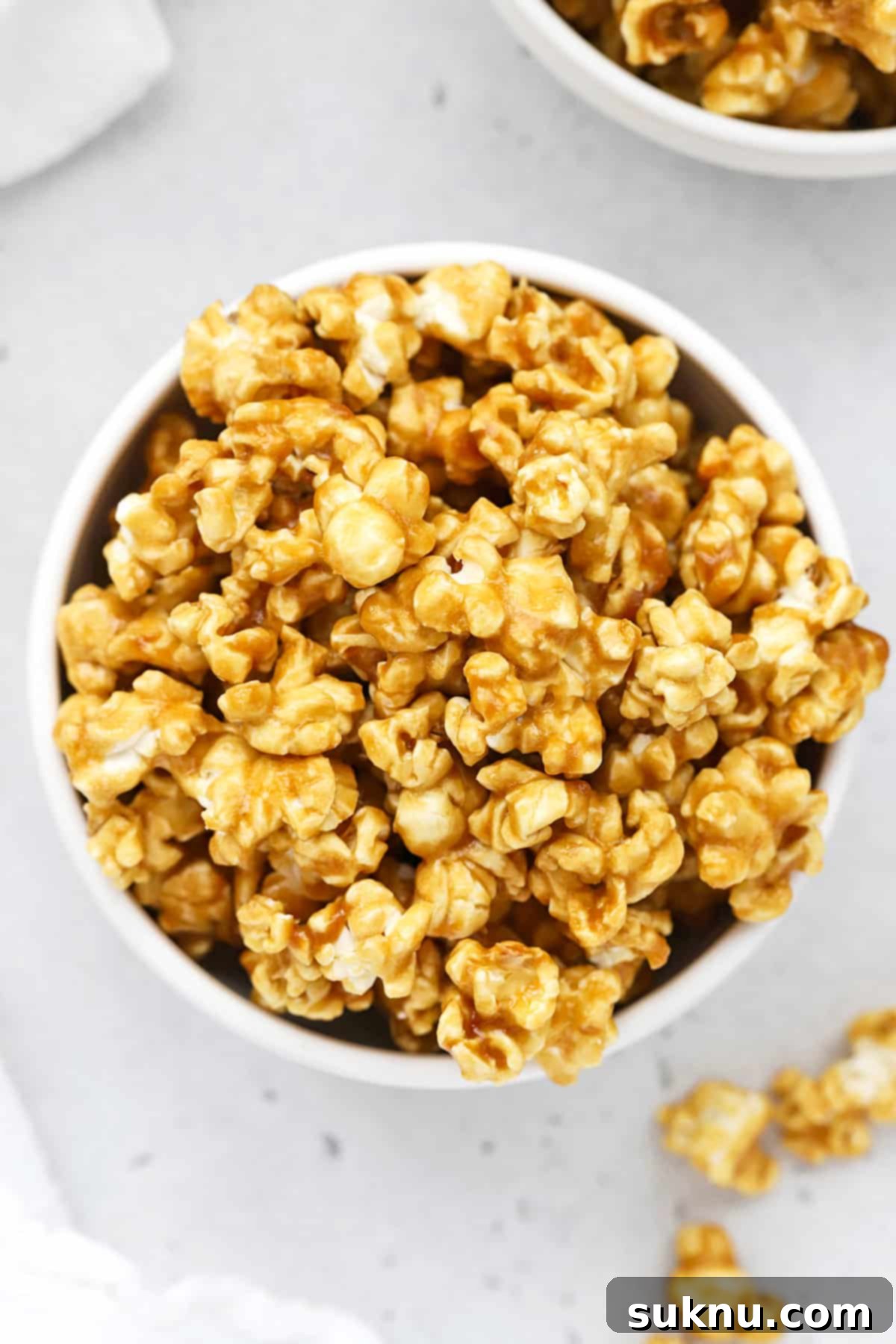 overhead view of two white bowls of crispy homemade caramel corn