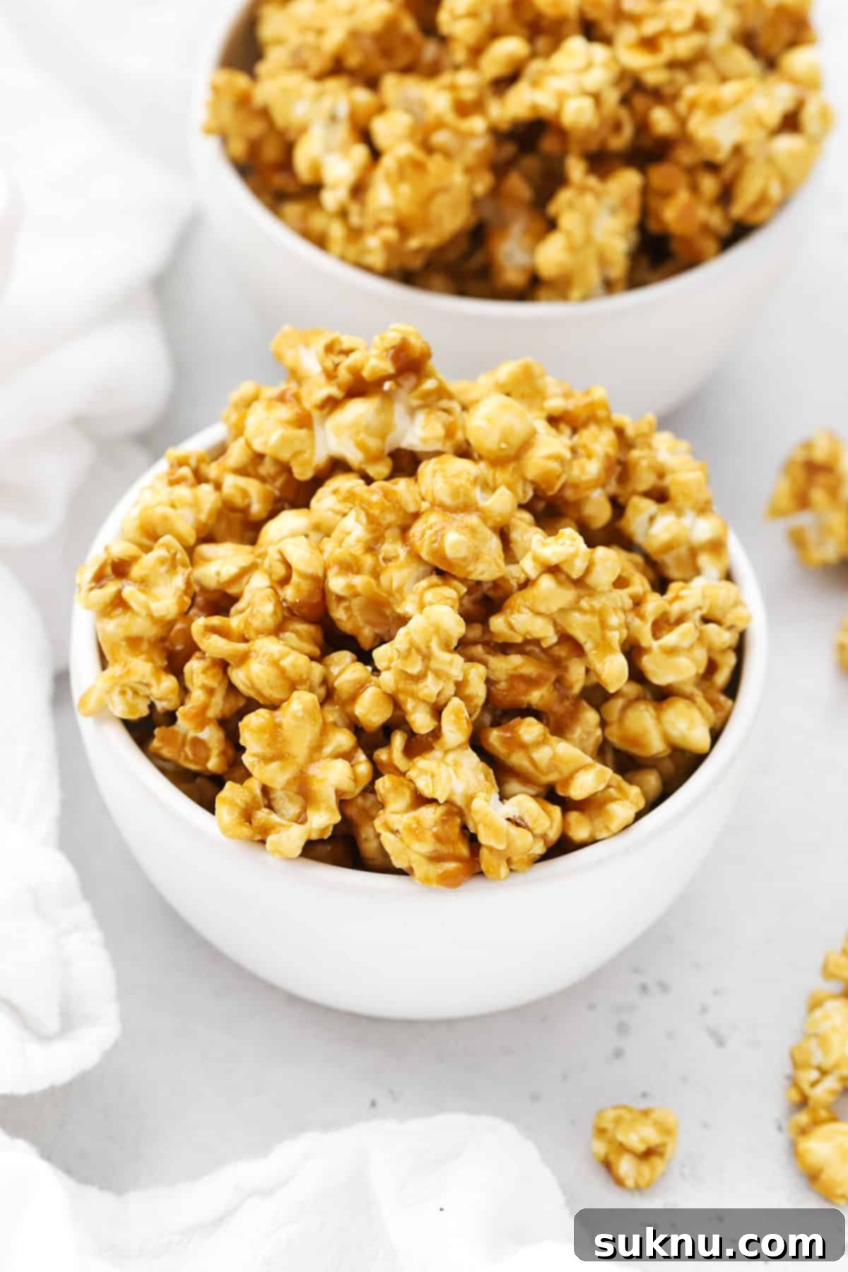 Front view of two white bowls of homemade caramel popcorn