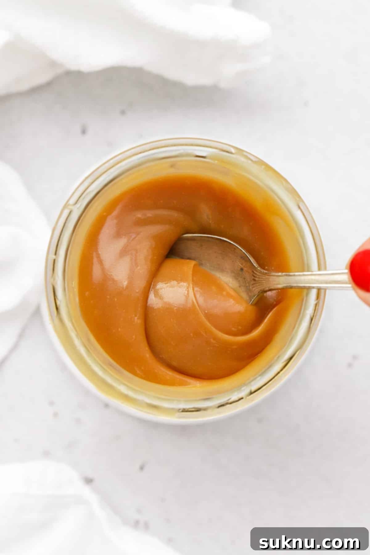 Using a spoon to stir easy homemade caramel sauce in a saucepan.
