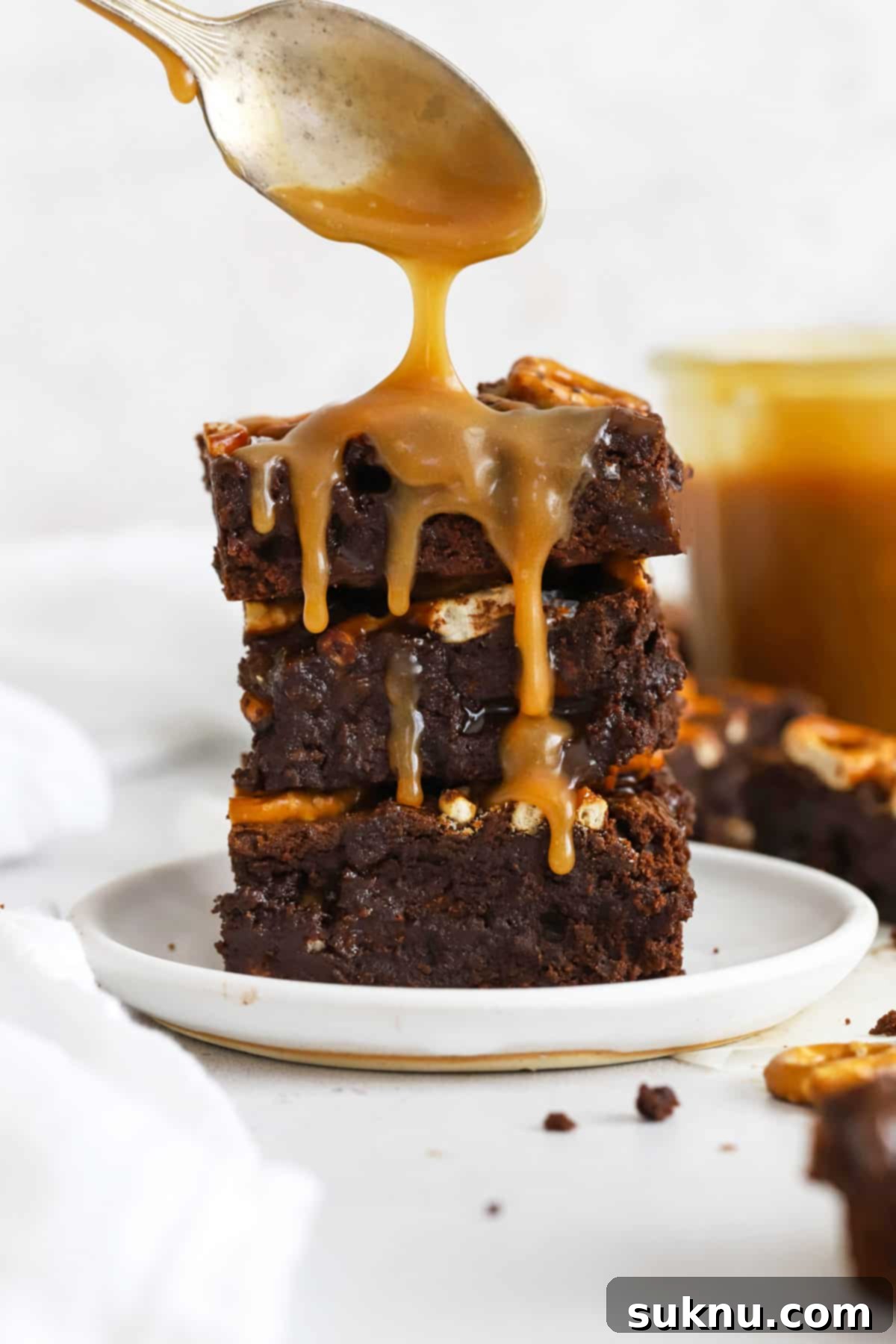 Decadent Gluten-Free Caramel Pretzel Brownies drizzled generously with homemade caramel sauce, showcasing their fudgy texture and crispy pretzel topping.